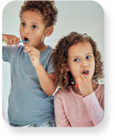 A brother and sister brushing their teeth together.